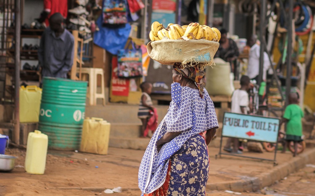 An old woman carries bananas in the market.